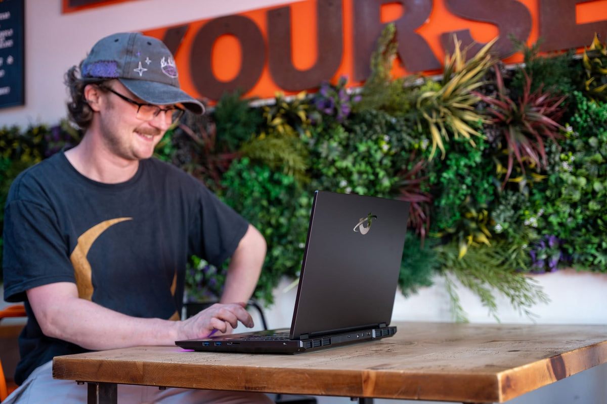 Sean - Utopia Technican working on laptop with flowers in background.