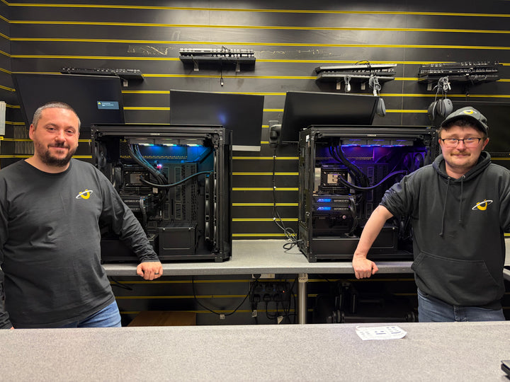Two Utopia Computers team members standing behind custom gaming PCs in the Kilmarnock showroom and workshop.