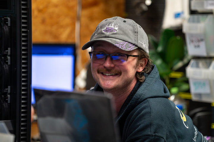 Utopia Computers team member smiling at his desk in the Kilmarnock workshop.